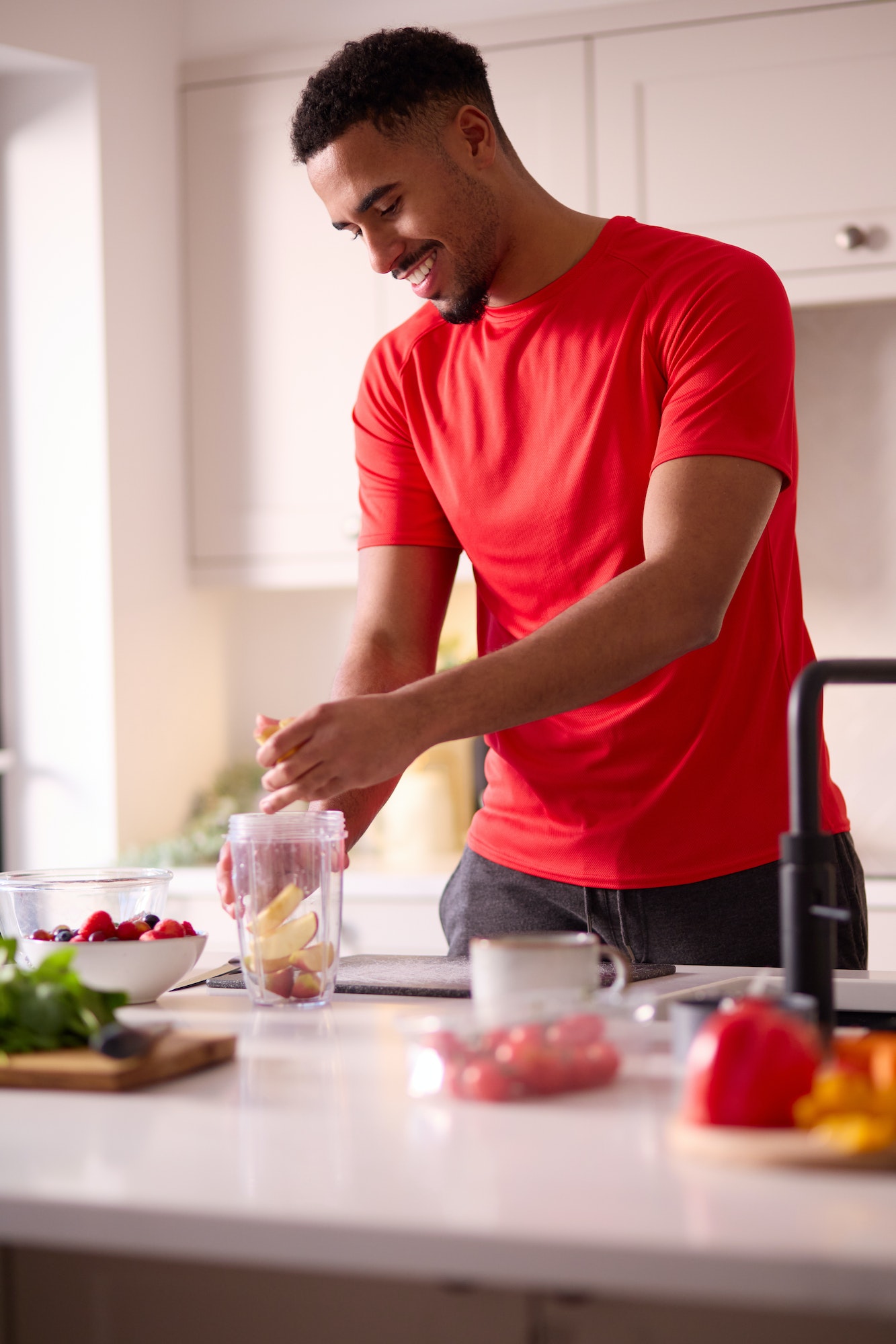 Man In Kitchen At Home Wearing Fitness Clothing Blending Fresh Ingredients For Healthy Drink